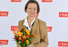 Martina Zöllner mit Blumenstrauß vor RBB-Wand