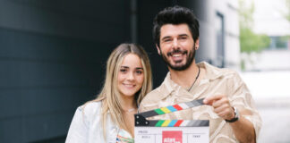 Antonia Kolano und Riccardo Angelini halten eine Filmklappe in der Hand