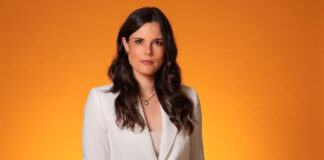 Linda Mürtz, neue Explosiv-Moderatorin, steht vor einem orangen Hintergrund.