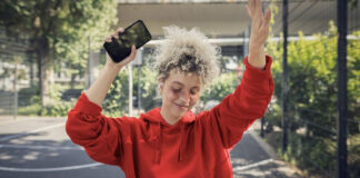 Eine Frau mit Smartphone tanzt.