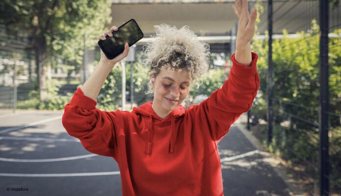 Eine Frau mit Smartphone tanzt.