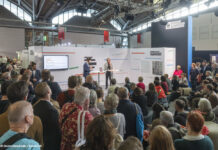 Ein Stand des Deutschlandradios auf der Frankfurter Buchmesse, Publikum hört einem stehenden Redner zu