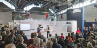 Ein Stand des Deutschlandradios auf der Frankfurter Buchmesse, Publikum hört einem stehenden Redner zu