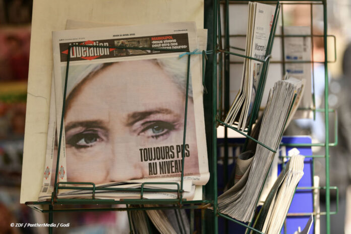 Bild einer französischsprachigen Zeitung im Ständer, auf der ersten Seite ein Foto von Marine Le Pen