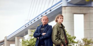 Die beiden Ermittler des TV-Krimis Stralsund stehen vor einer Brücke und gucken in die Kamera