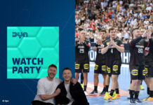 Die Moderatoren der Dyn Watch Party lachen in die Kamera, im Hintergrund die deutsche Handballnationalmannschaft der Herren nach einer Partie auf dem Spielfeld.