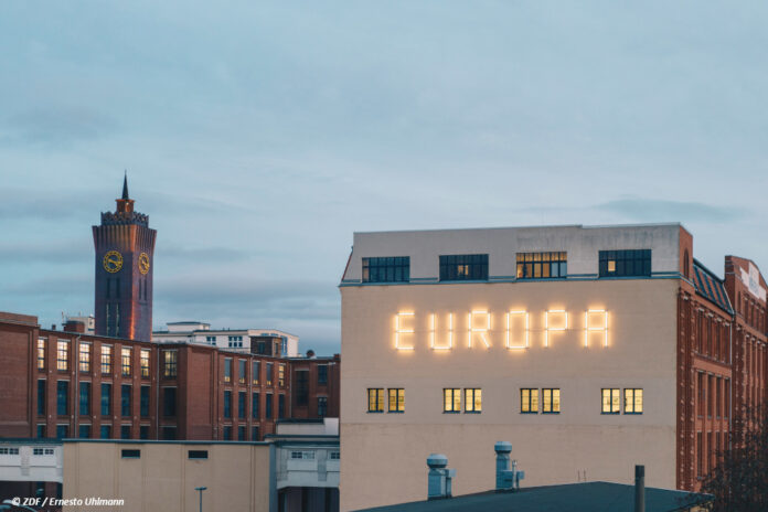 Ein Leuchtschriftzug "EUROPA" auf der Fassade eines Hauses.