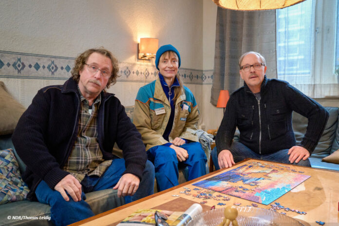 Bjarne Mädel, Katharina Marie Schubert und Olli Dittrich sitzen in ihren Kostümen auf einer Couch bei Dreharbeiten