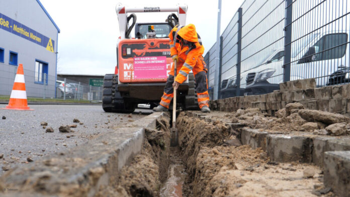 Glasfaser-Ausbau: Ein Bauarbeiter gräbt eine Mulde für Telekom-Glasfaserkabel.